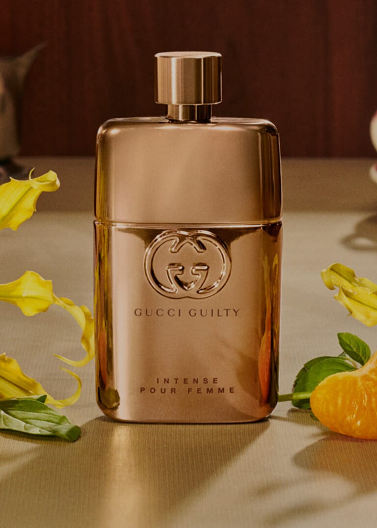 Elegant Gucci perfume bottle with yellow flowers and an orange slice.