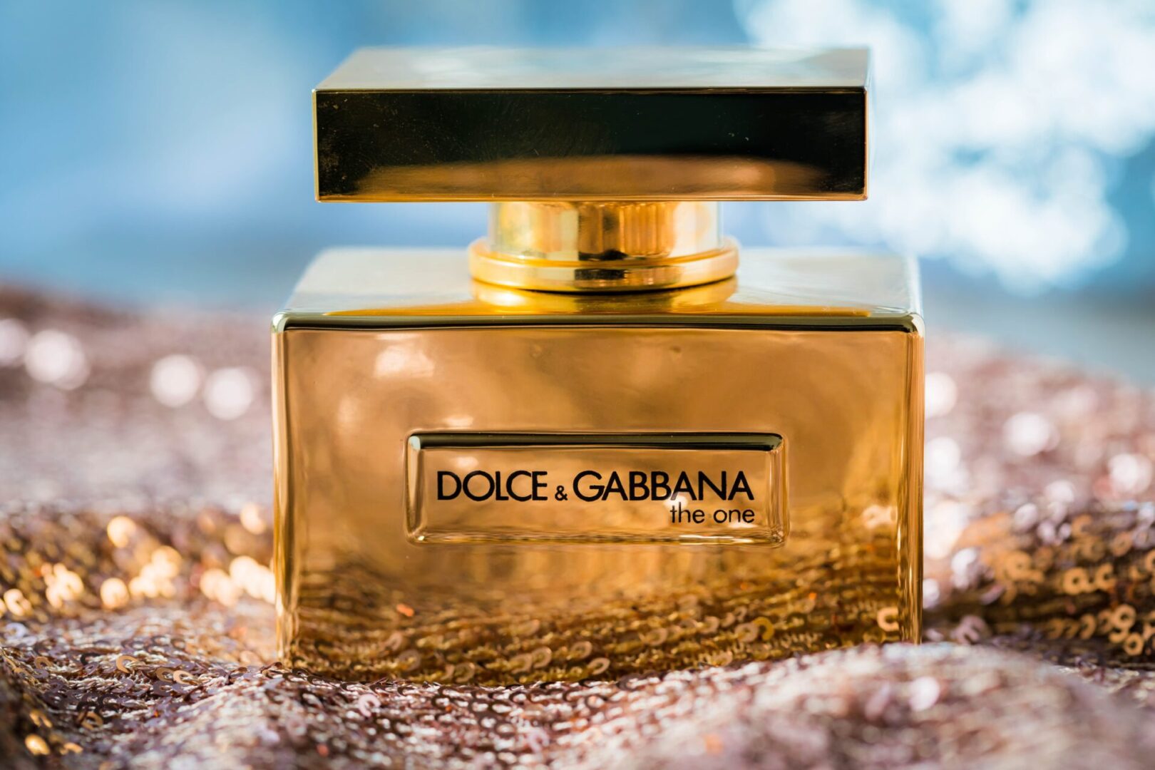 A gold Dolce & Gabbana perfume bottle with a reflective background.